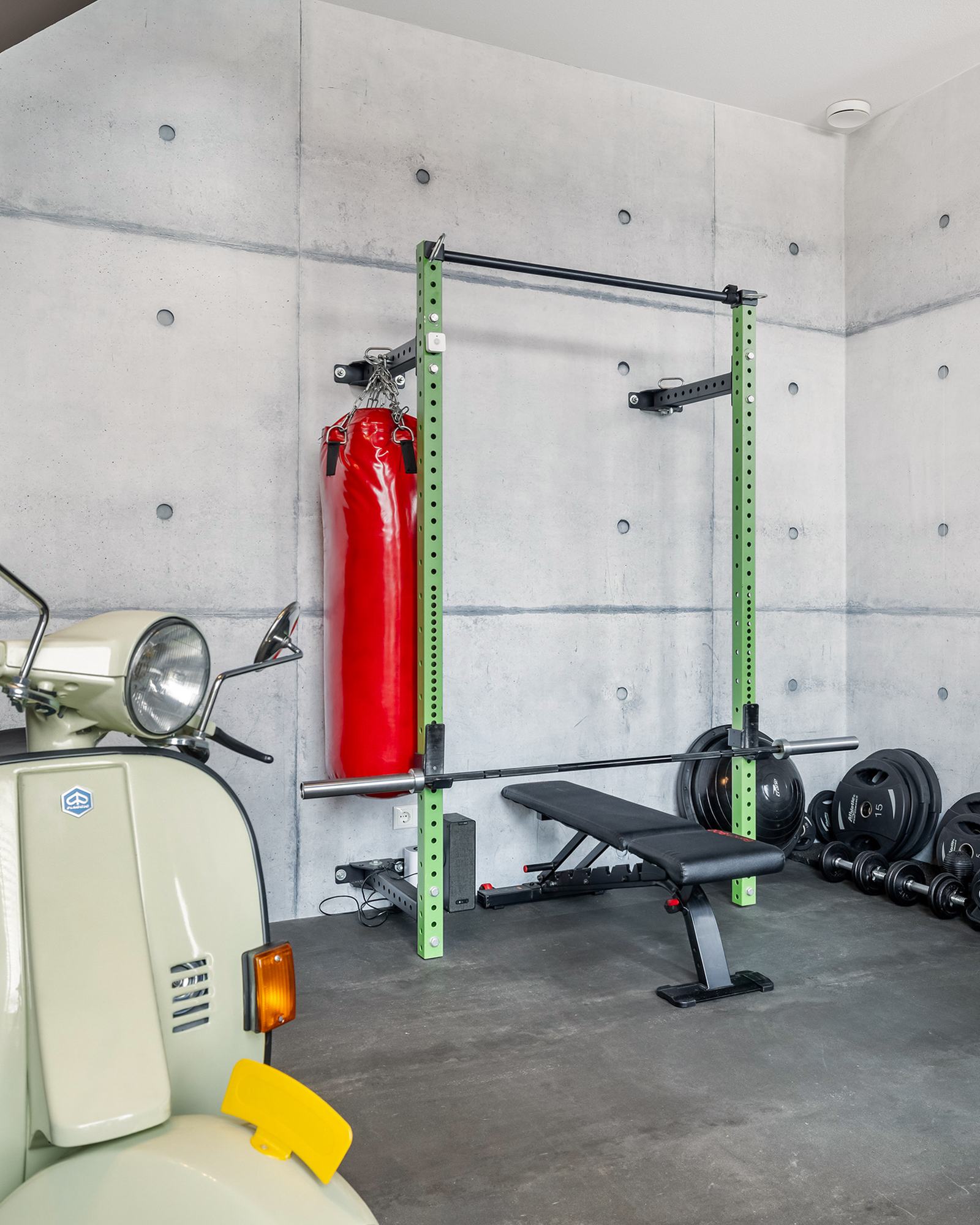 Eigen gym met krachtrack, gewichten en bokszak tegen betonlook wand